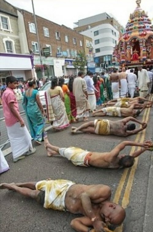 Men rolling on tarmac on Uxbridge road, London to pay tribute to Lord Murugan for Thaipusam festival